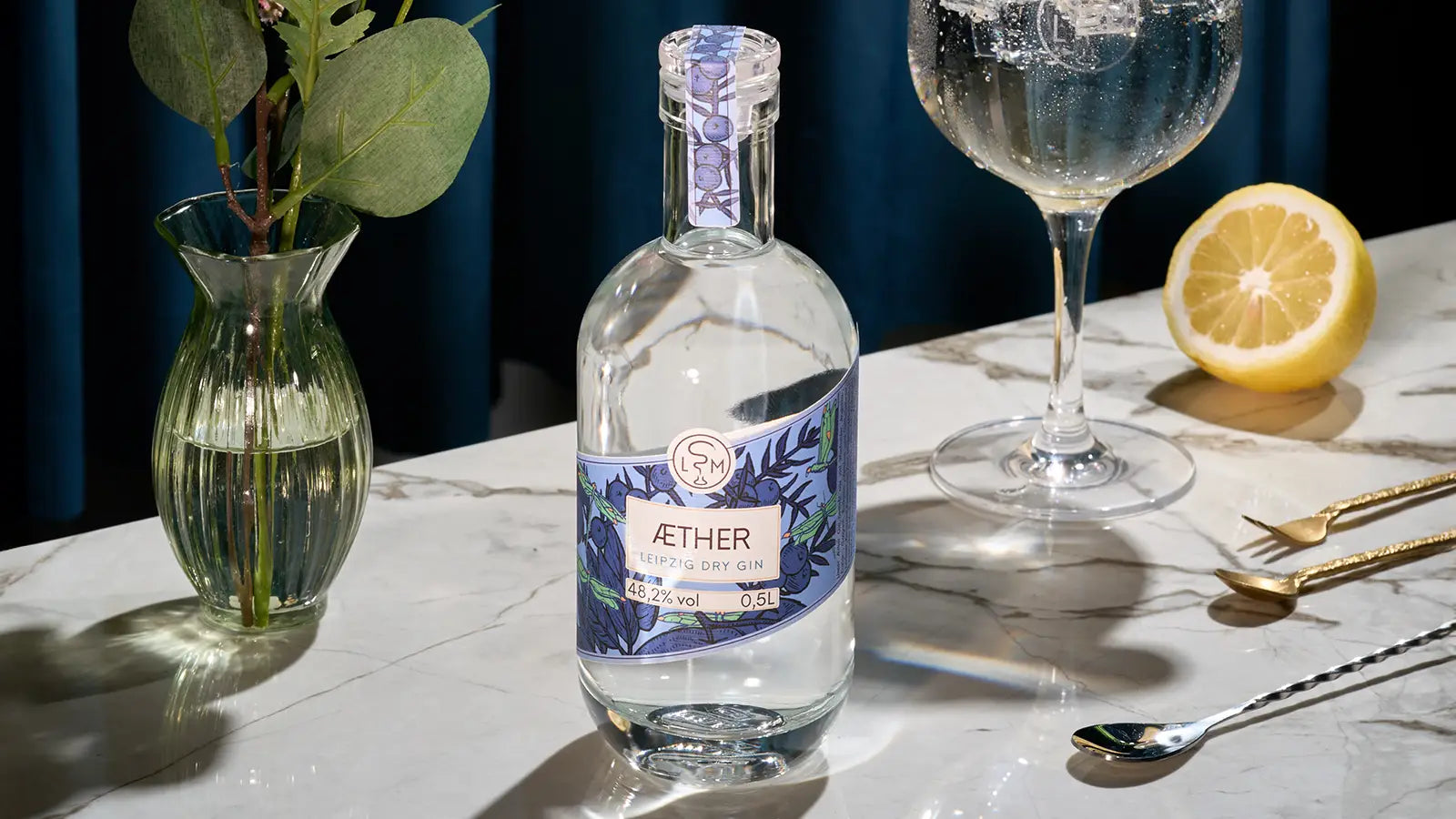 Aether Gin auf Marmortisch mit Zitrone und Gin Tonic Glas als edles Moodbild