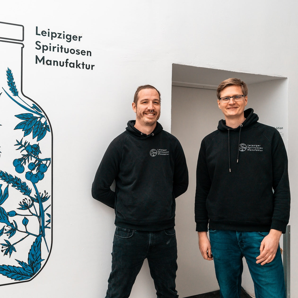 Die Gründer vor dem Firmenlogo der Leipziger Spirituosen Manufaktur