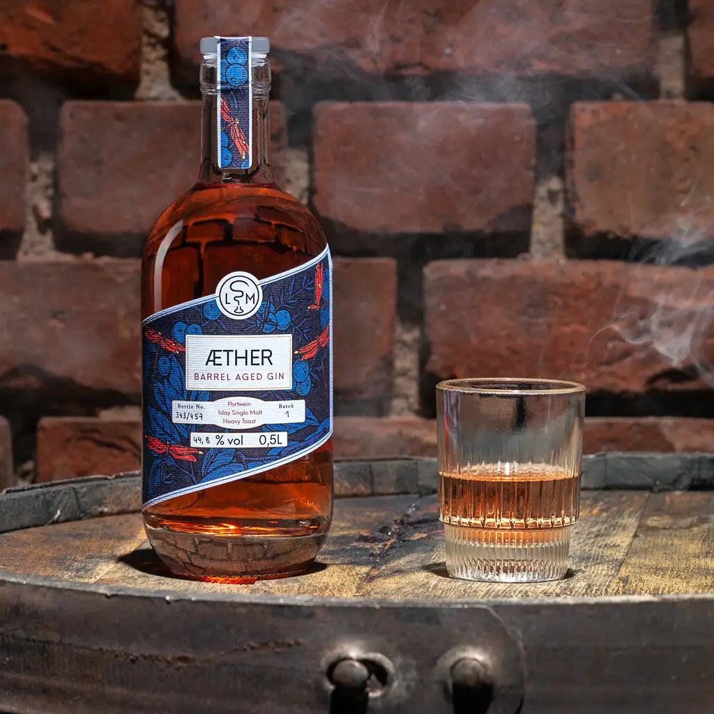 Aether Barrel Aged Gin als fassgelagerter Gin vor Ziegelsteinwand und Holzfass inszeniert als Moodbild