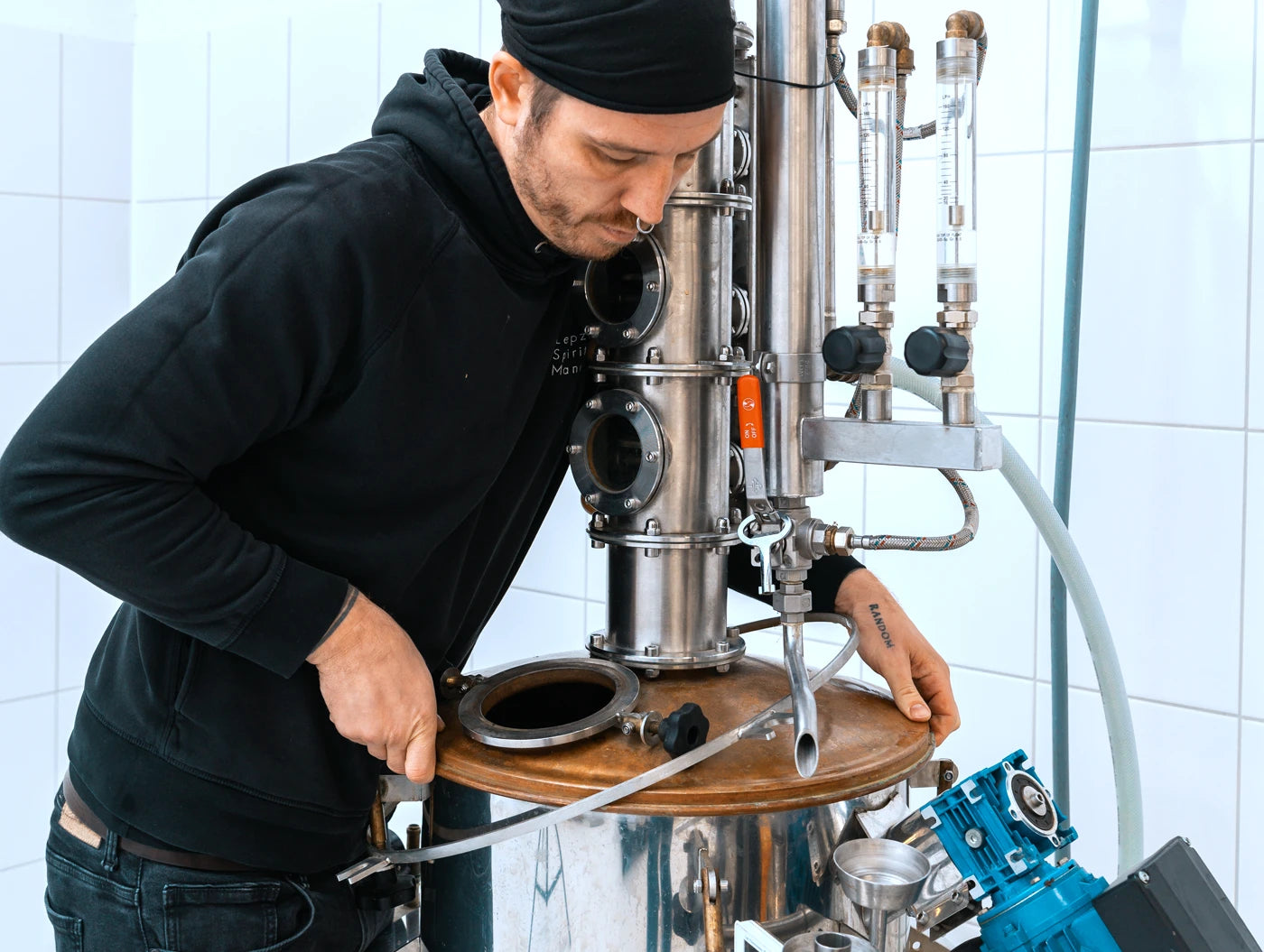 Mitarbeiter bereitet die Destille vor und setzt den Helm auf für handwerkliche Destillierkunst in der Leipziger Spirituosen Manufaktur