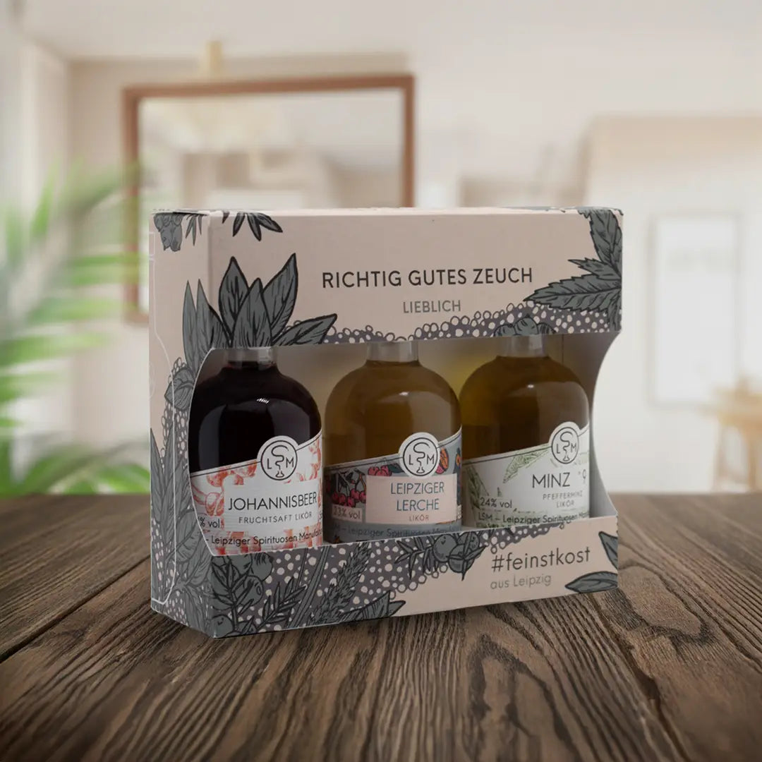 Tastingset Lieblich in Geschenkverpackung mit Johannisbeerlikör, Leipziger Lerche Likör und Minzlikör auf einem Tisch präsentiert