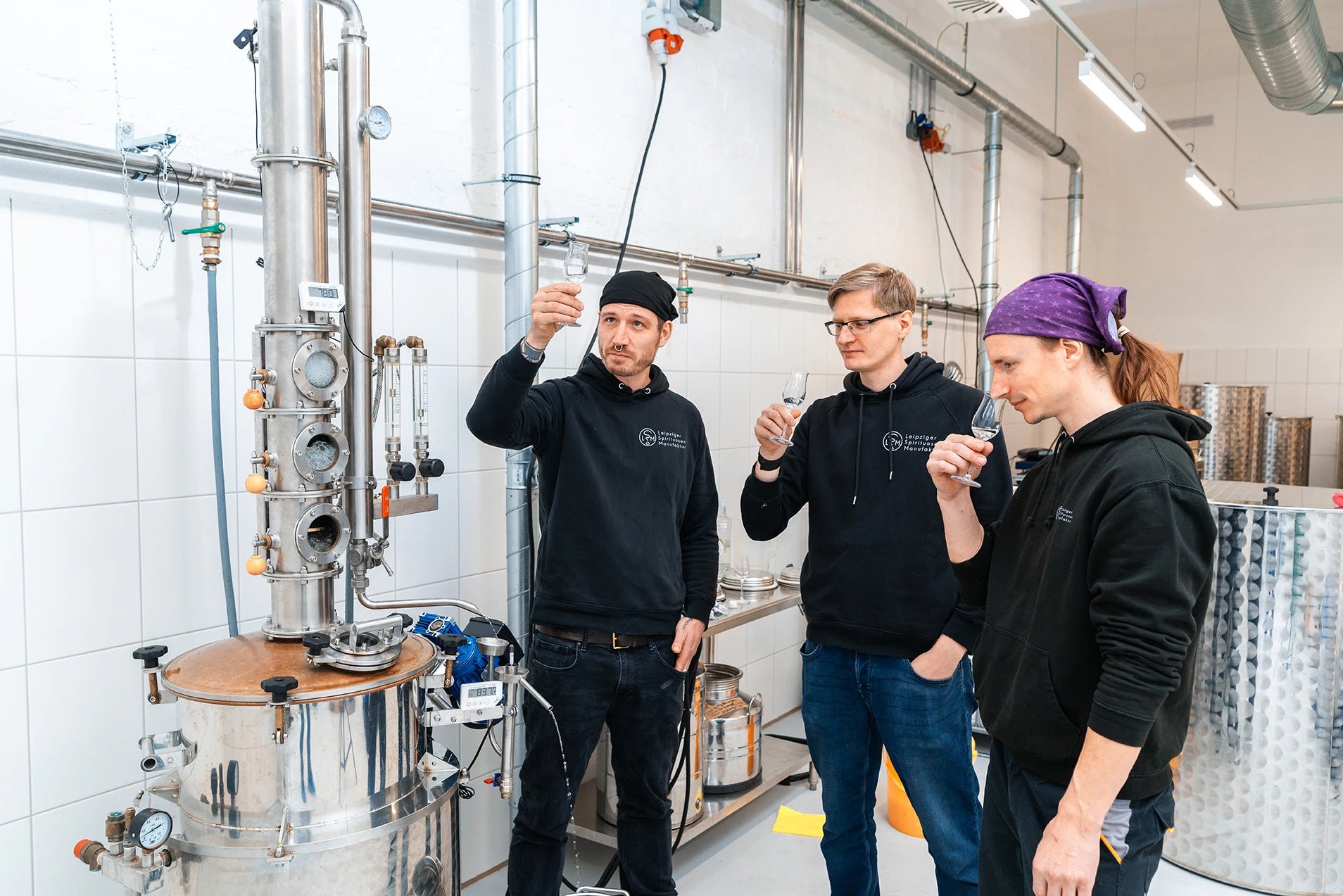 Drei Mitarbeiter verkosten eine Spirituose mit Nosinggläsern an der Destille in der Leipziger Spirituosen Manufaktur