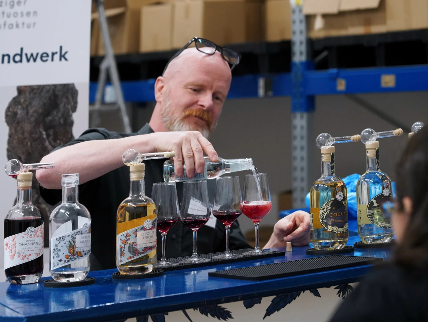 Mitarbeiter schenkt bei einer Führung einen Willkommensdrink mit Johannisbeerlikör und Tonic aus